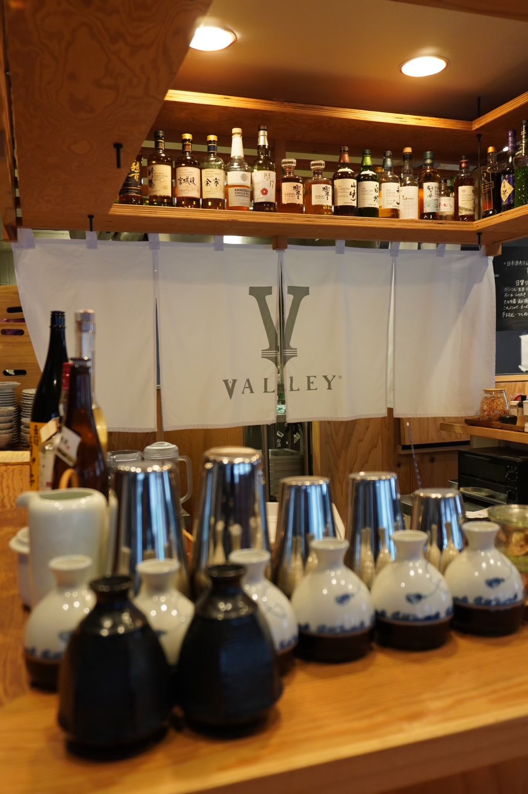 VALLEYの暖簾と酒器が並ぶカウンター